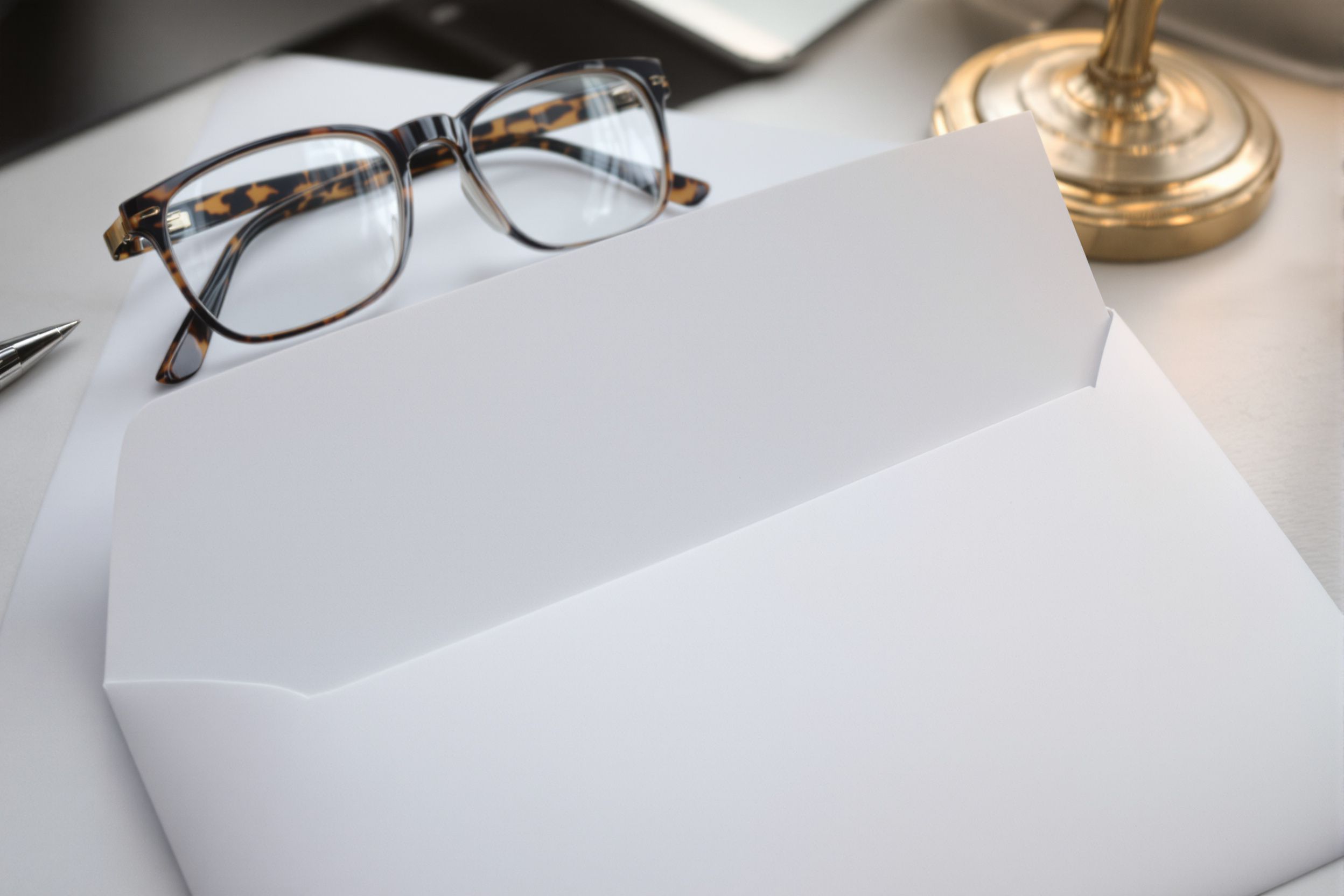 An opened business envelope and folded letter with glasses resting on it