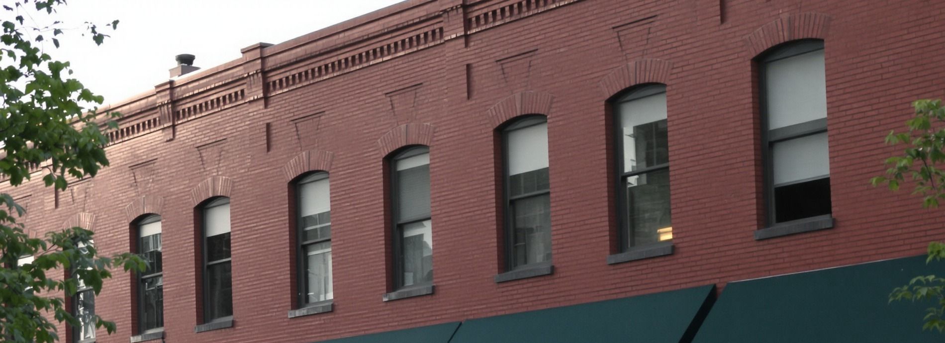 Upper floors of a red brick main street building with tall arched windows